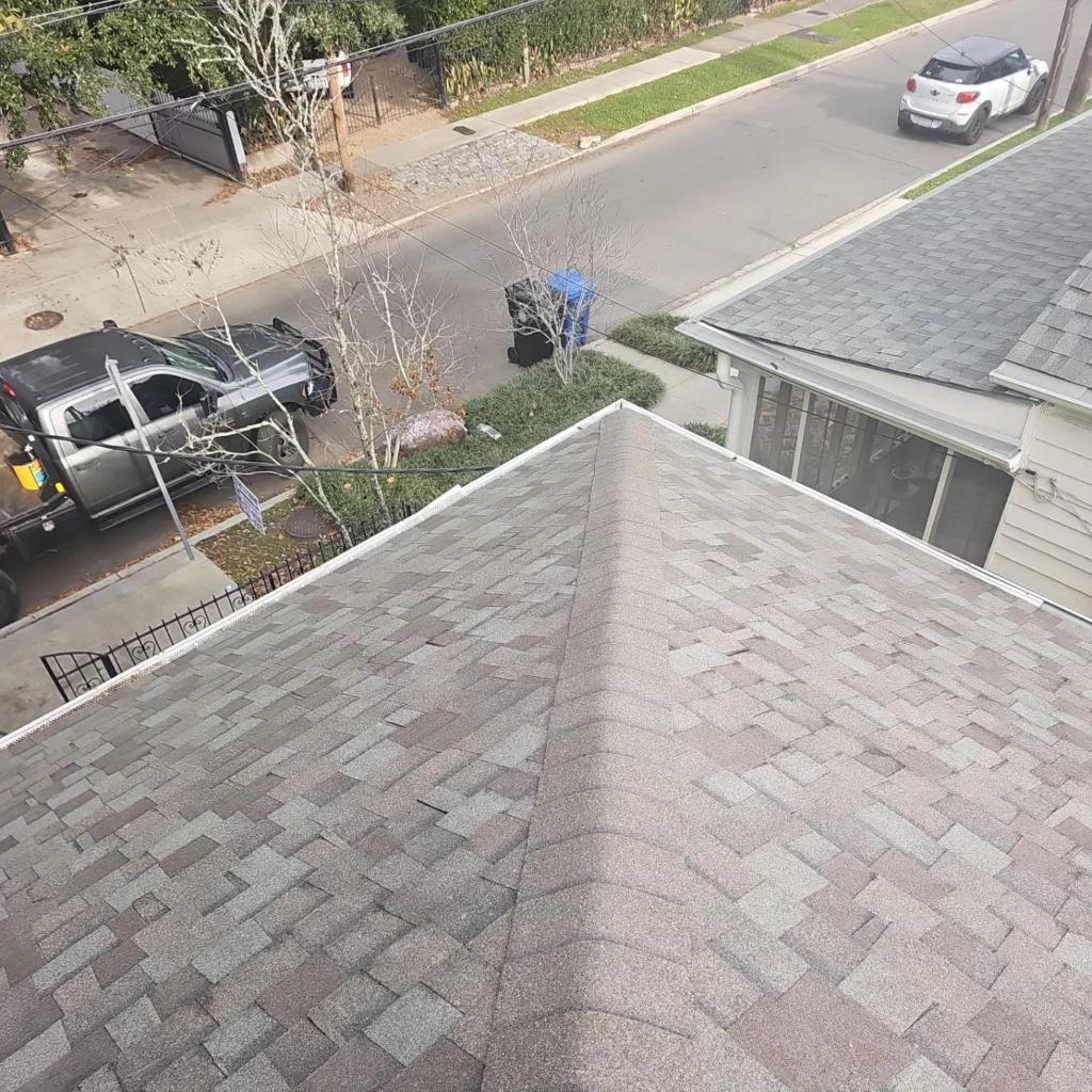 Aerial view of completed Owens Corning Driftwood architectural shingle roof replacement on historic French Quarter residential property with street below.