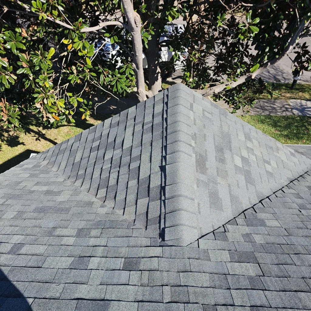 Gray architectural shingle hip roof with sealed ridge, fortified installation, residential home, tree-lined yard, Kenner LA