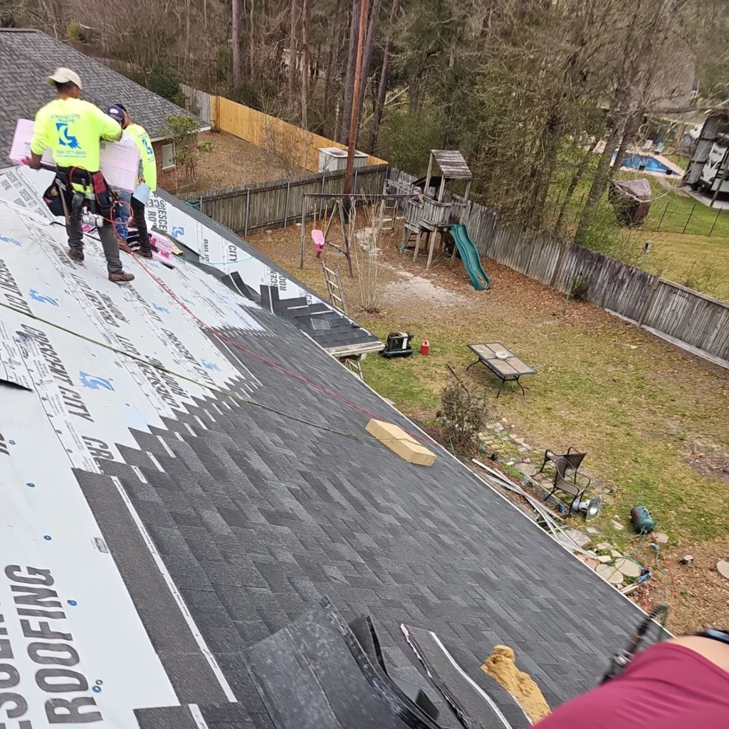 Roofers installing OC Onyx Black architectural shingles on large residential roof with Crescent City Roofing underlayment, backyard visible below.