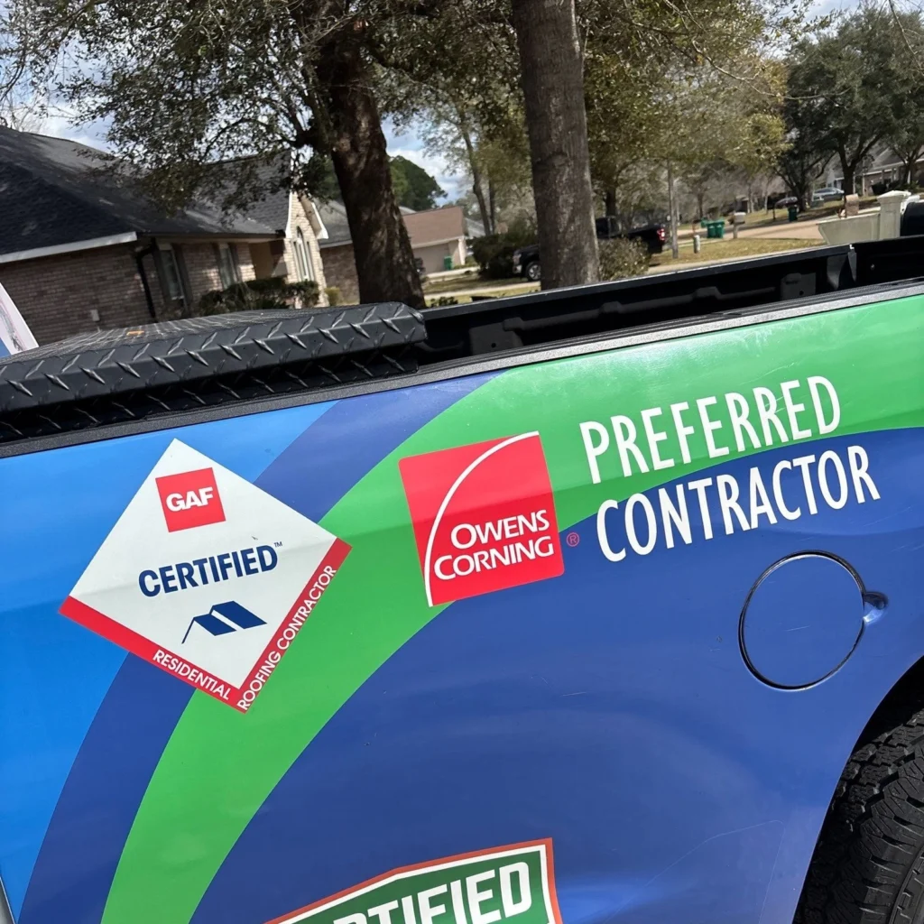 GAF Certified and Owens Corning Preferred Contractor logos on a branded blue and green roofing truck in a residential neighborhood.
