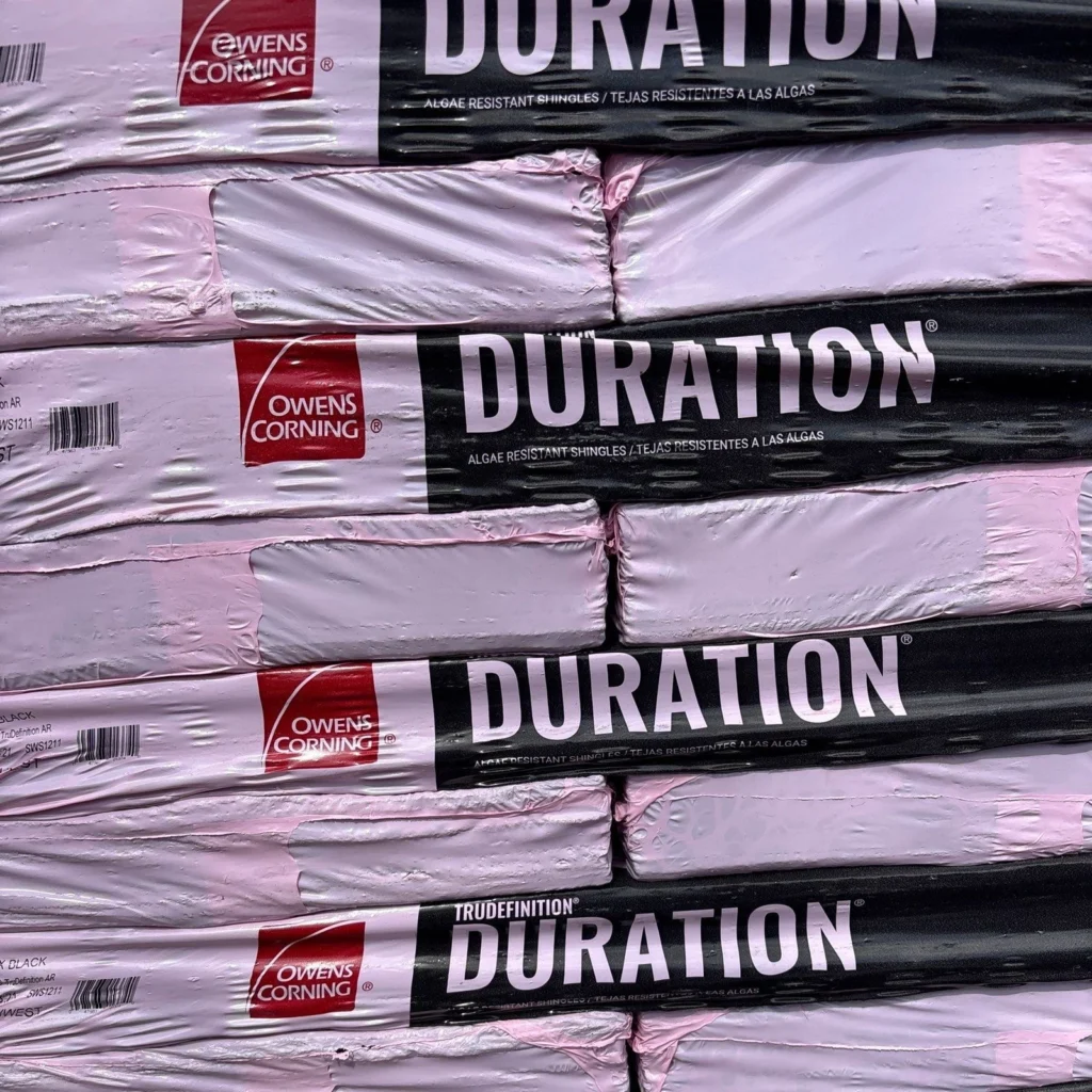 Stacked pallets of Owens Corning TruDefinition Duration algae-resistant roofing shingles in Onyx Black for large residential roof replacement.