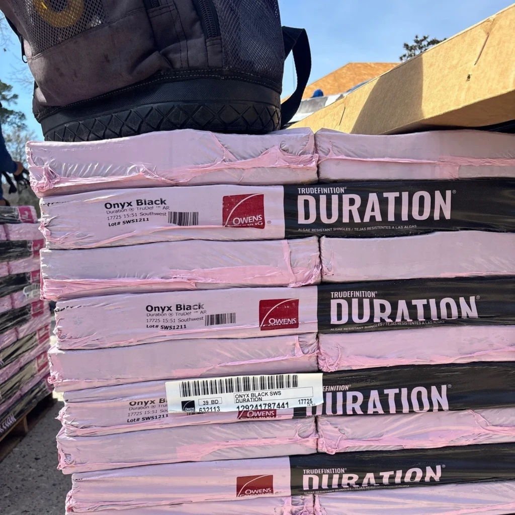 Stacked pallets of Owens Corning TruDefinition Duration Onyx Black algae-resistant architectural shingles for large residential roof replacement in Slidell.