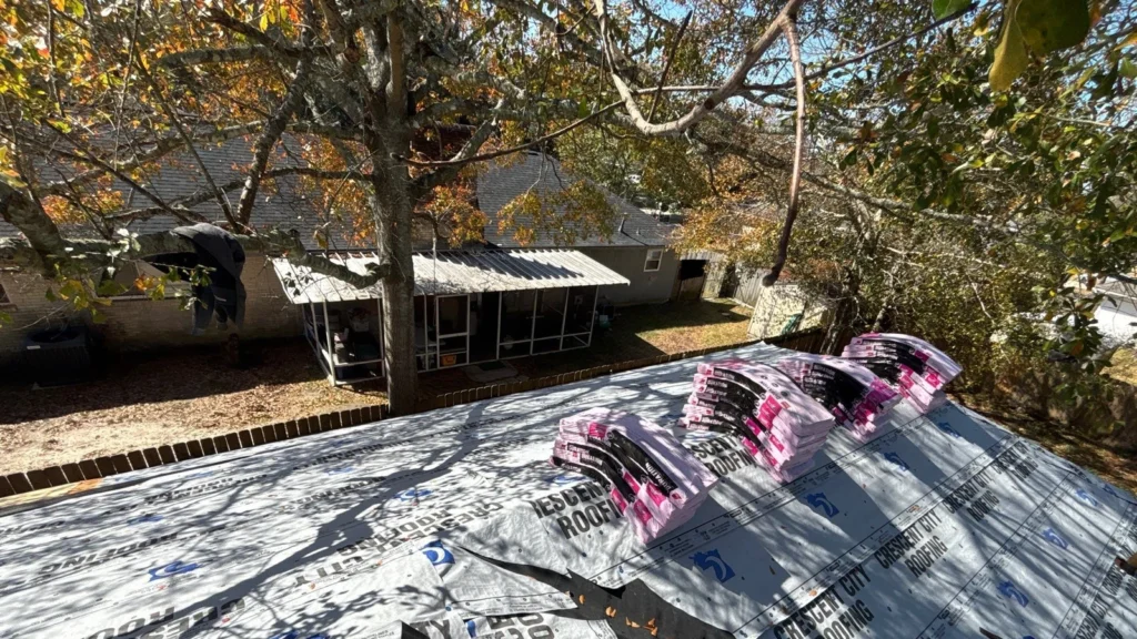 Crescent City Roofing underlayment installed on residential roof with stacked Owens Corning Onyx Black shingle bundles, Slidell backyard view