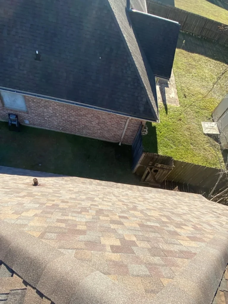 Aerial view of large residential roof replacement using Owens Corning Teak architectural shingles beside dark-shingled neighbor home, Slidell LA.