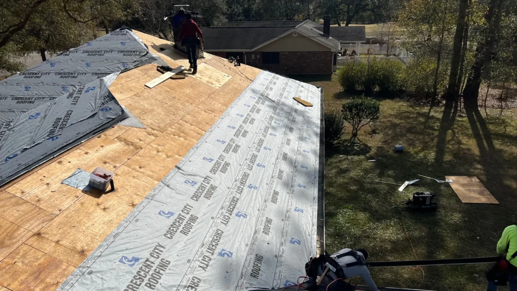 Crescent City Roofing crew installing underlayment on large residential roof deck during OC Estate Gray shingle replacement, Slidell