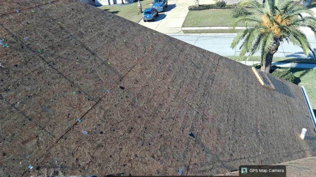 Bare OSB roof decking with chalk lines and staples visible on large residential home before OC Teak shingle installation, Slidell LA