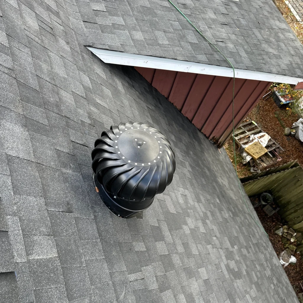 Black turbine roof vent installed on dark gray OC Onyx Black asphalt shingles, residential FORTIFIED roof replacement, Slidell