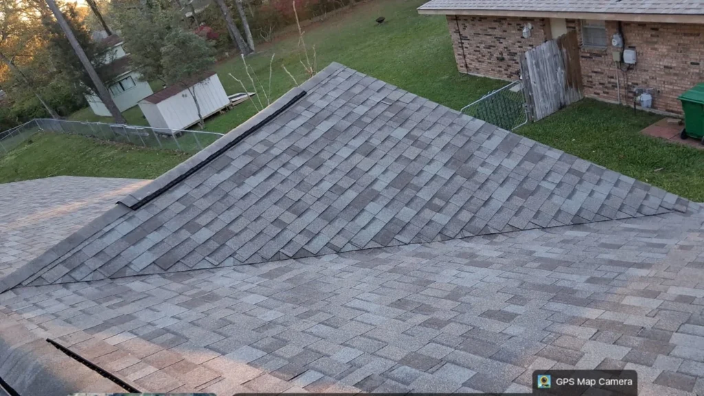 Completed residential roof replacement with OC Driftwood architectural shingles, hip and valley detail, Slidell home backdrop.