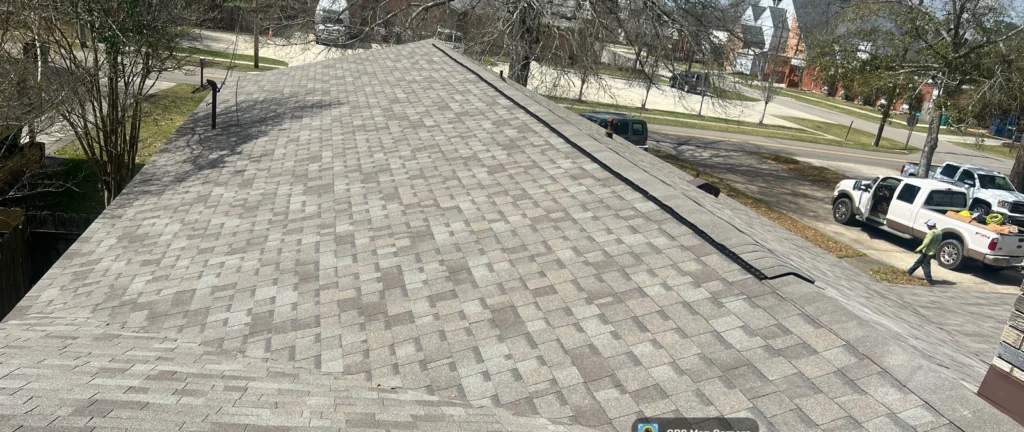 Large residential roof replacement with OC Driftwood gray asphalt shingles, Slidell home, worker and truck visible streetside.